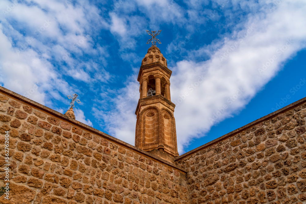 Viev of Mor Gabriel Monastery of Mardin Province, beautiful stone architecture tower wall and door with blue sky with clouds Viev of Mor Gabriel Monastery of Mardin Province, beautiful stone architecture tower wall and door with blue sky with clouds