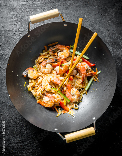 Chinese Udon noodles in a wok pan with chopsticks.