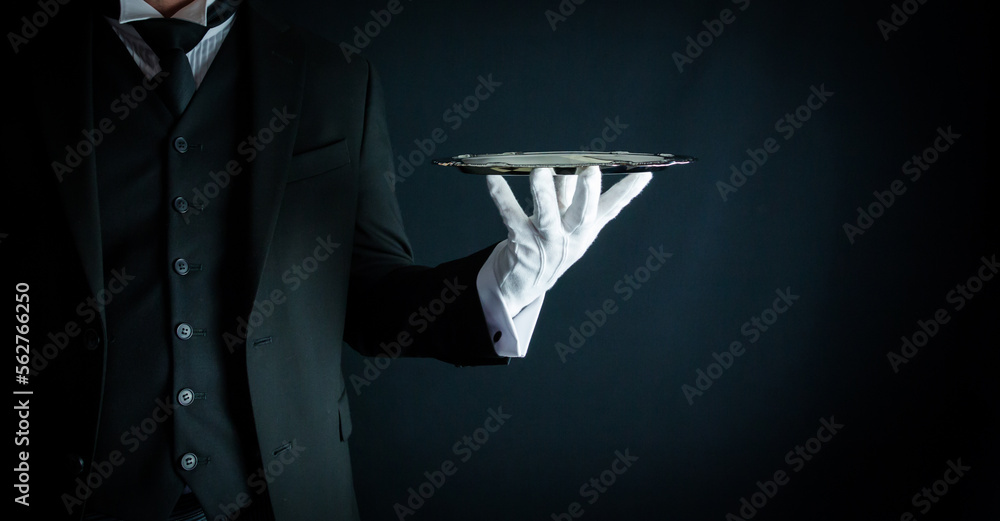 Portrait of Butler in Formal Attire and White Gloves Holding Silver Serving Tray on Black Background. Service Industry and Professional Hospitality - obrazy, fototapety, plakaty 