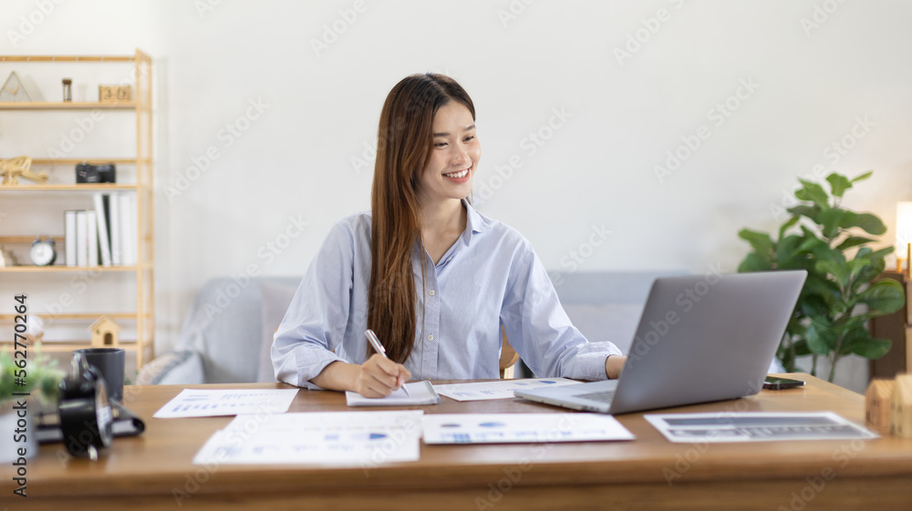 Beautiful young asian woman watching live video or video call of teacher teaching on laptop in her home, Take notes of important conversations and messages during the teacher's teaching. Beautiful young asian woman watching live video or video call of teacher teaching on laptop in her home, Take notes of important conversations and messages during the teacher's teaching.