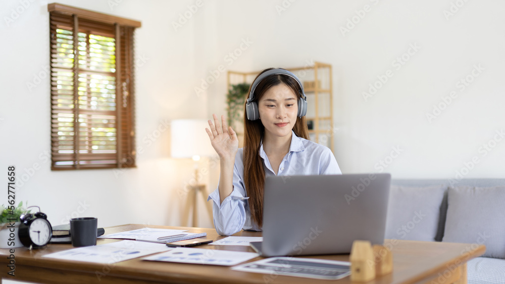 Asian female college student wearing headphones watching live performance or video call teacher teaching on laptop, Conversations with teachers and classmates, Online learning, Study at your own home. Asian female college student wearing headphones watching live performance or video call teacher teaching on laptop, Conversations with teachers and classmates, Online learning, Study at your own home.