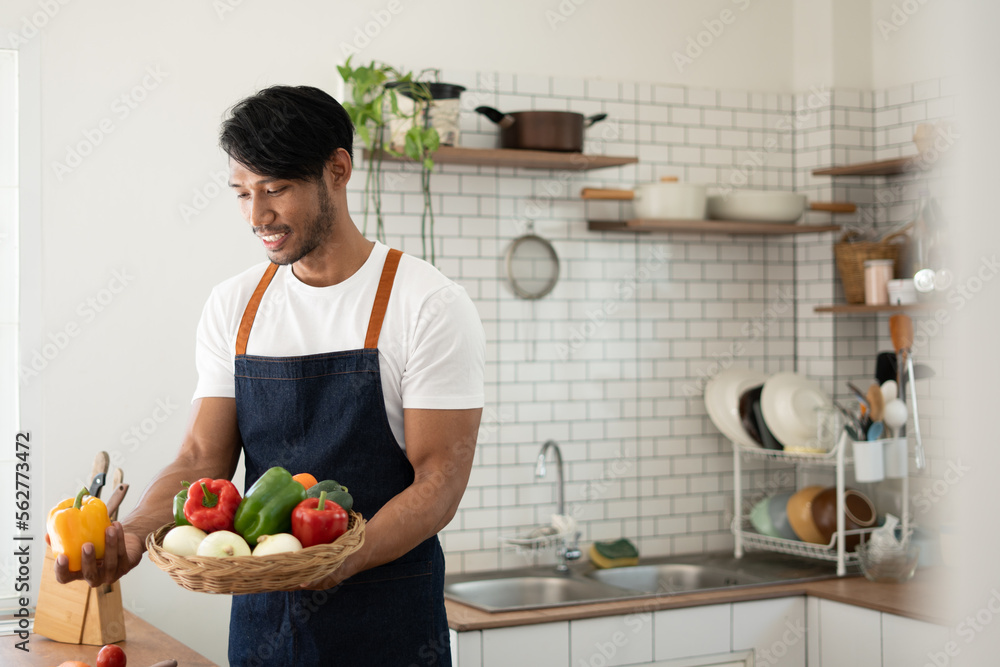 Handsome asian man cooking at home preparing salad in kitchen. Handsome asian man cooking at home preparing salad in kitchen.
