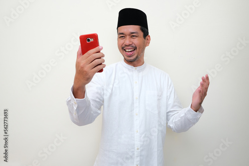 Moslem Asian man showing happy face expression when looking to his mobile phone photo