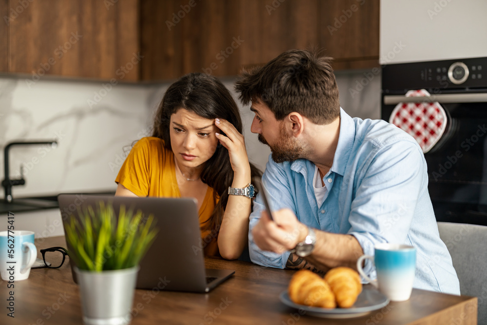 Unhappy, stressed and upset couple paying bills with a laptop