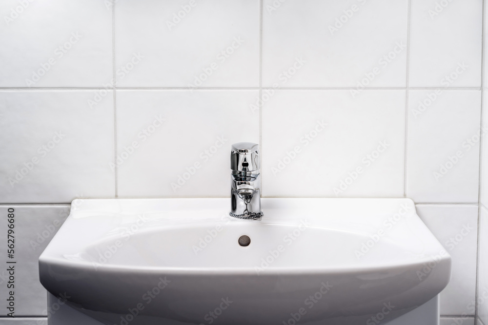 Bathroom sink. Toilet faucet, water tap and WC basin. Public, home or hotel  room restroom interior design. Light and clean. Washing hands in washroom  concept. Family apartment. White tile wall. foto de