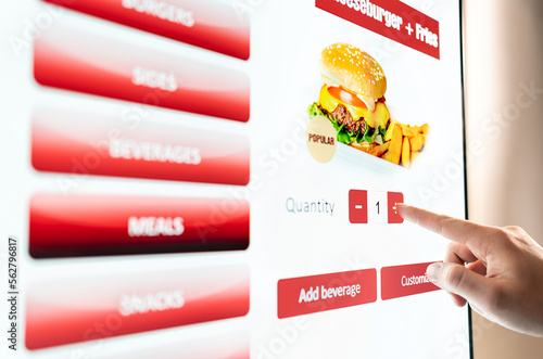 Self service order kiosk and digital menu in fast food burger restaurant. Touch screen in vending machine. Man using electronic selfservice technology and buying meal and paying. photo