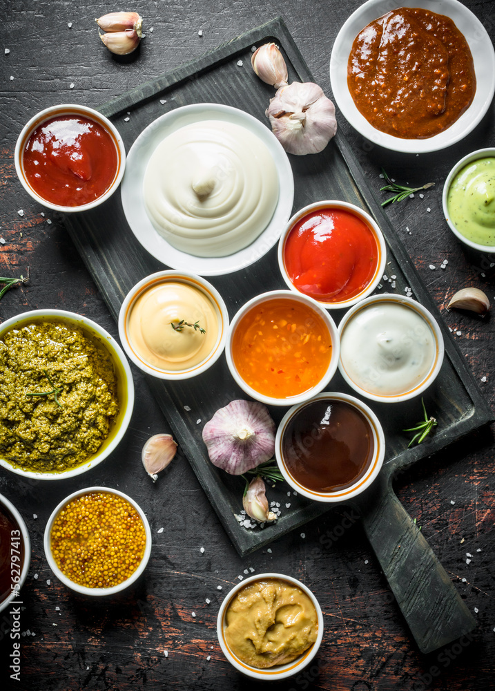 Pesto sauce, guacomole, ketchup, mustard, barbecue sauce in bowls.