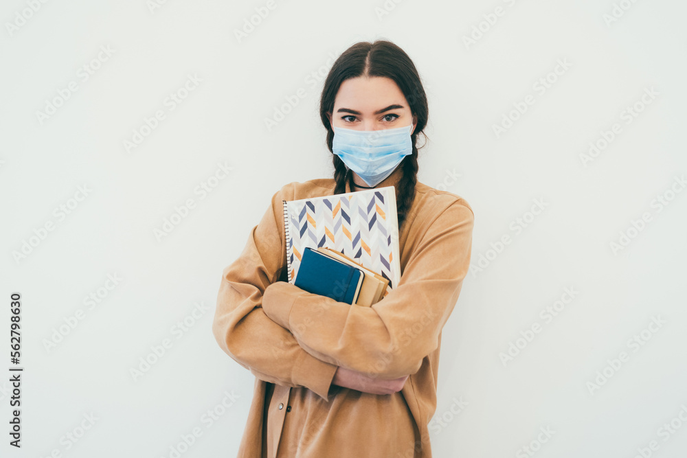 Young student in a protective mask with books Young student in a protective mask with books