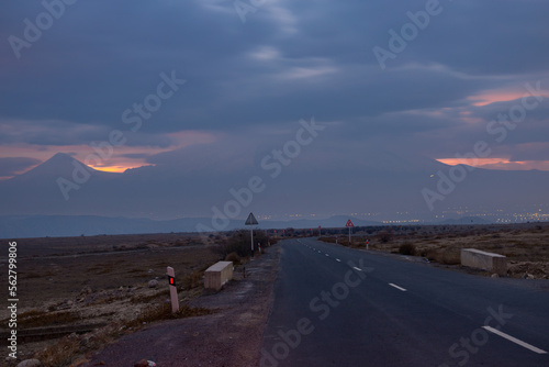 Asphalt road against backdrop of dramatic cloudy colorful sunset on a winter day