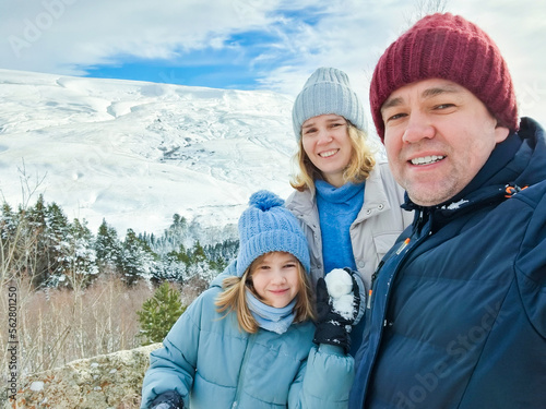 selfie mom, dad and daughter on a walk through the snow-capped mountains. family winter trips and hikes.