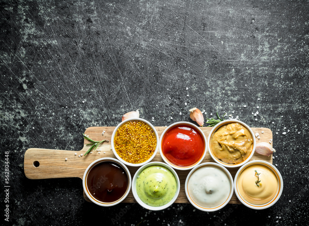 Sauces on a wooden cutting Board with garlic and rosemary. Sauces on a wooden cutting Board with garlic and rosemary.