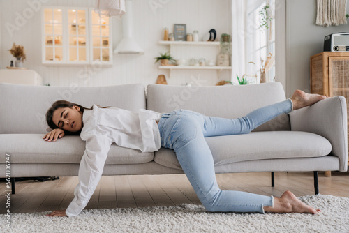 Tired woman in white shirt and blue jeans have sleeping on sofa. Tired female lying at home alone in kitchen, feels mental or physical exhaustion. Lack of energy after sleepless night, fatigue concept