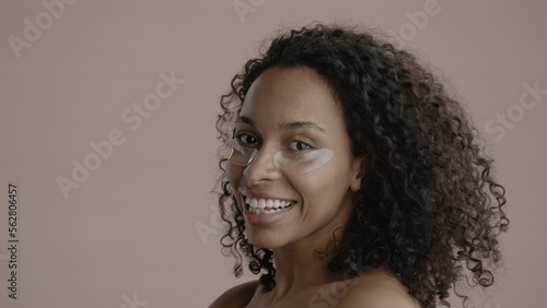 CU Portrait of attractive African-American female doing her skincare routine. Applying eye patches. Soft studio lighting. No make up, clean skin. Shot with ARRI Alexa Mini LF