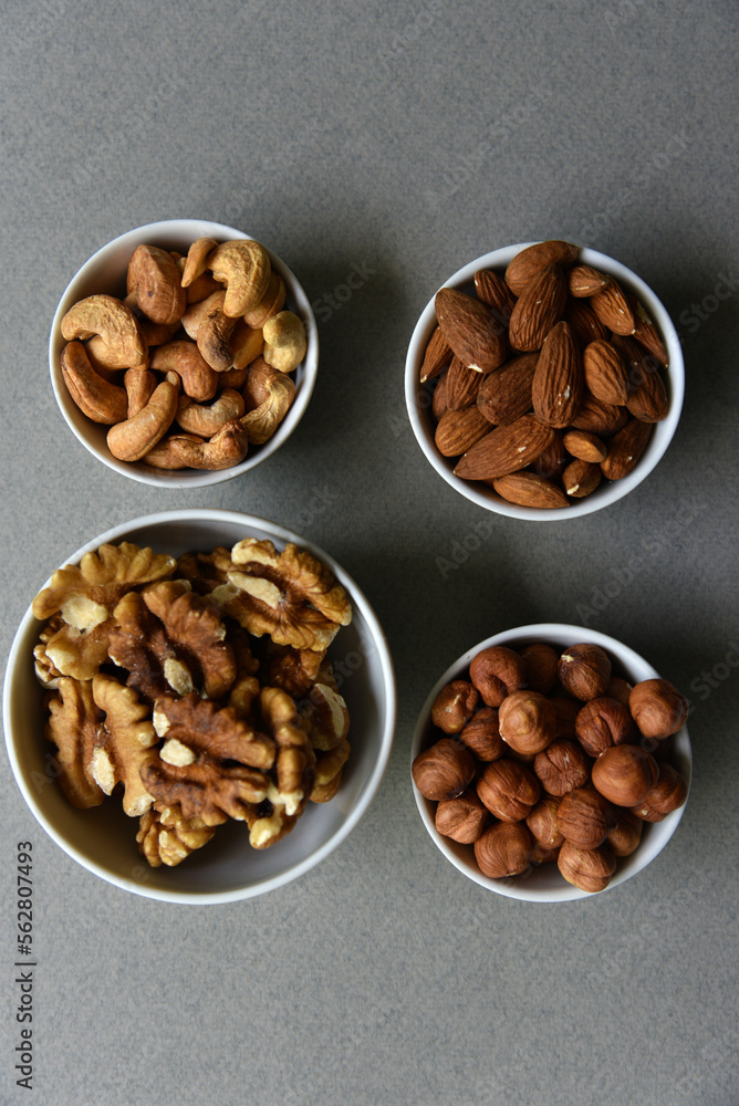A set of nuts in white cups on a black background. Peanuts, hazelnuts and almonds. Walnut. A delicious set of nuts. A set of nuts in white cups on a black background. Peanuts, hazelnuts and almonds. Walnut. A delicious set of nuts.