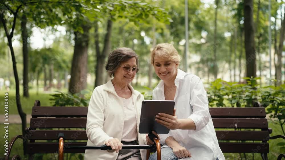 Smiling senior woman and daughter making a video call to relatives using tablet