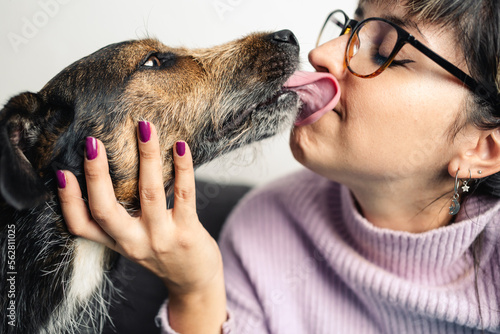 Crossbreed dog licking and kissing Latin woman in the face. Adoption awareness concept