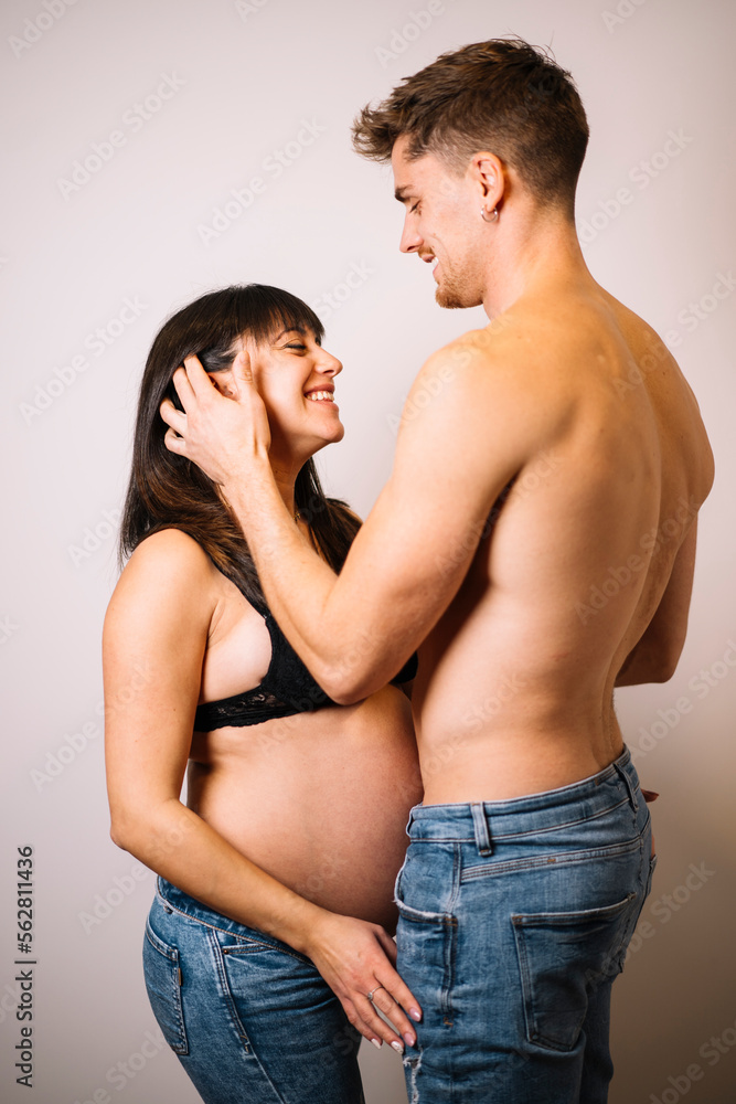 Happy couple expecting baby embracing in studio Happy couple expecting baby embracing in studio