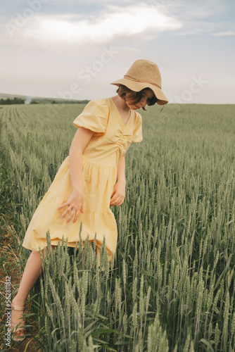 portrait of a beautiful girl in a yellow dress and hat with a bouquet of flowers in the field