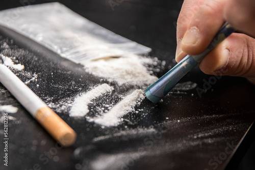 Drug Addiction: Close-up of person using a 20 euro note to snort cocaine on a black table