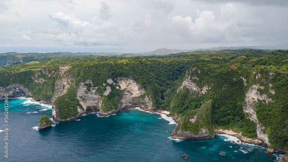 Beautiful coastline aerial view from Saren Cliff Point. Clear water and rocks with cloudy sky. Nusa Penida, Indonesia.