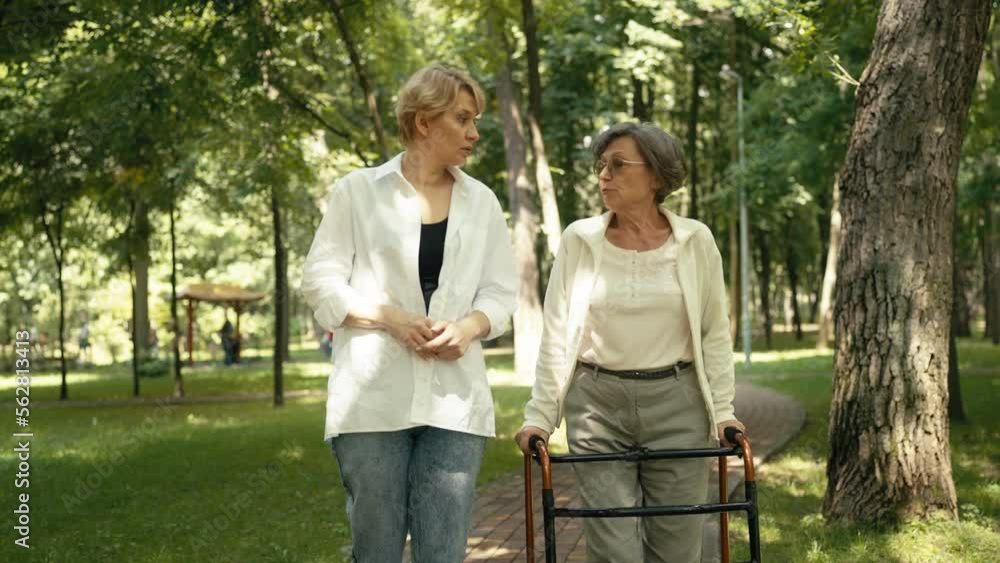 Senior woman with disability walking and talking with her friend in a park Senior woman with disability walking and talking with her friend in a park