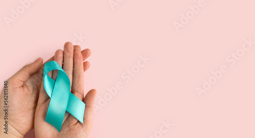 Woman holding Teal ribbon. Symbolic for cervical cancer, ovarian cancer, gynecological cancer and PCOS. And sexual assault awareness. photo