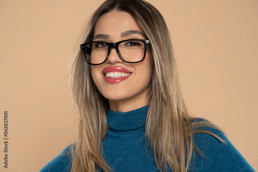 Young smiling woman wearing casual clothes and glasses looking to camera, relax profile pose with natural face and confident smile on a beige studio background