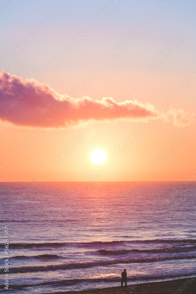 Male silhouette on the dawn on the sea. Morning walk on the beach. Romantic beautiful sunny background. Charging, sports, active lifestyle. Stunning sunrise Sea. Sun disc over the horizon.