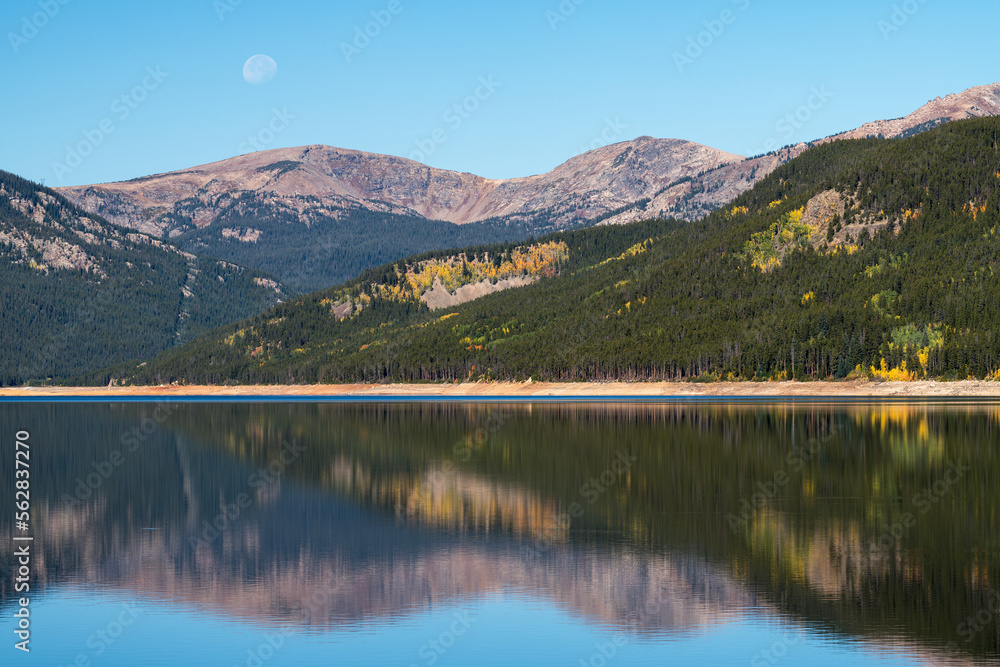 The moon is above 12,489 Foot Lyle Benchmark peak which is reflected on the still waters of Turquoise Lake, in the early autumn.