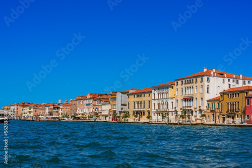 Airplane and seagulls in the blue sky over the sea and vintage houses along the Grand Canal in the city of Venice on a sunny day, the main sea street of Venice, architecture and sights of Italy