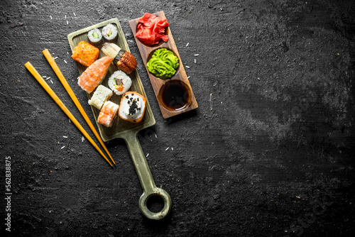 Sushi, rolls and maki on the cutting Board with chopsticks and sauces.