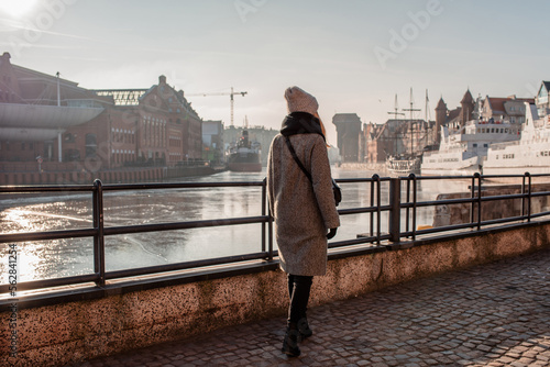Woman enjoys the panorama of the city of Gdansk. Amazing scenic view of the city. The girl explores Poland, Europe. City and sea. Urban autumn landscape, old historical architecture