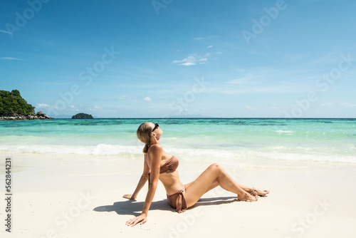Dream summer destination. Woman enjoying sunny tropical day and blue sky. Girl with tanned body.