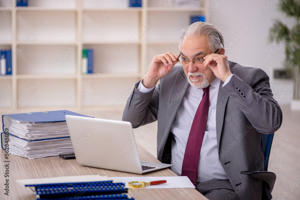 Fototapeta premium Old male employee working in the office