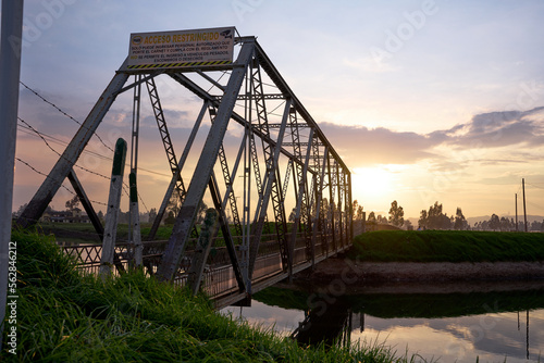 rural landscape. steel bridge over a river at sunset. rustic steel bridge over a quiet river. sunset by the river. 