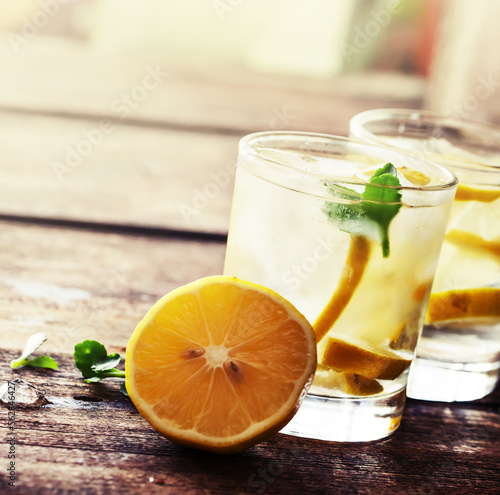 Glasses of water with lemon over rustic wooden background photo