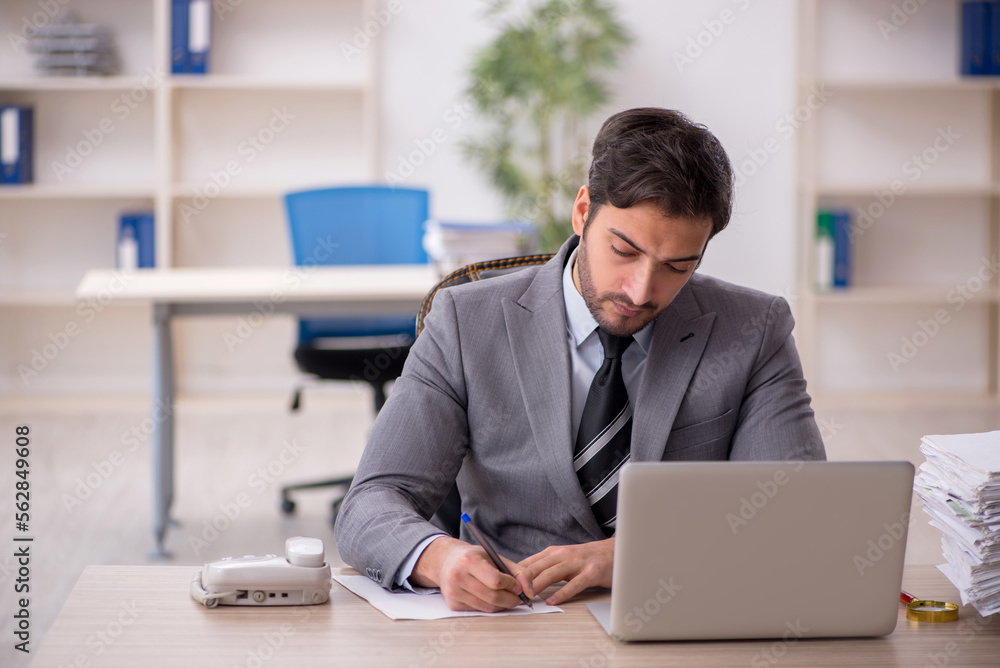 Young male employee and too much work in the office Young male employee and too much work in the office