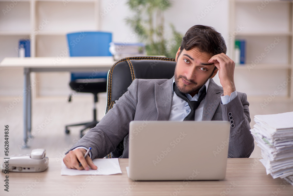 Young male employee and too much work in the office Young male employee and too much work in the office