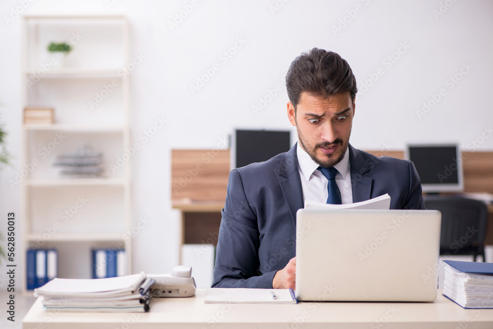 Young male employee sitting at workplace Young male employee sitting at workplace