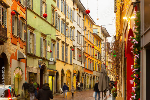 View of typical narrow cobbled street of historical Italian city of Bergamo with colorful buildings and traditional Christmas decorations during winter holidays © JackF