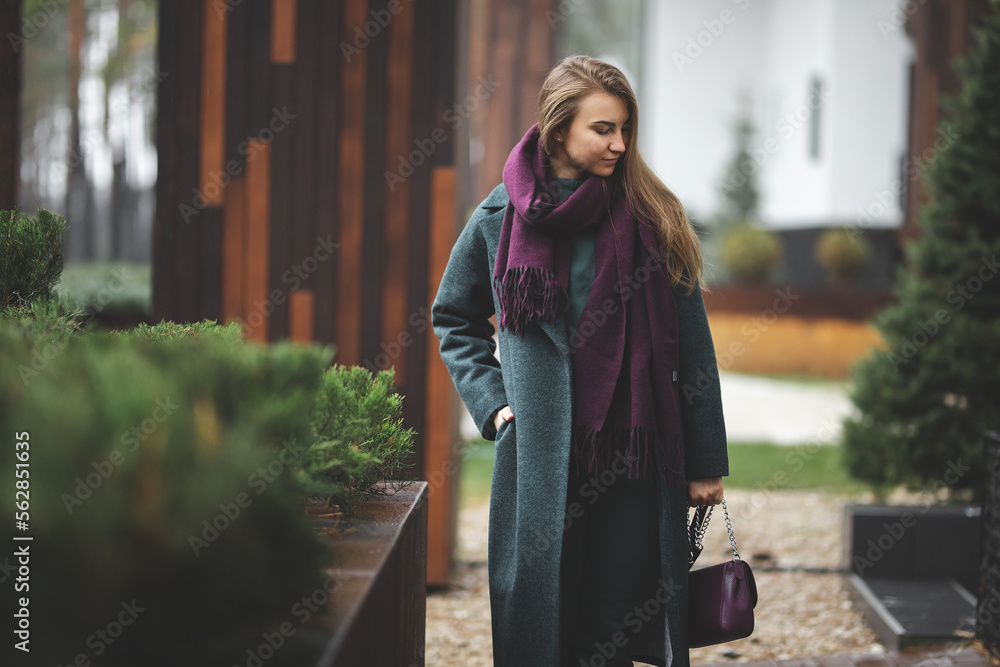 An attractive white Caucasian girl in an autumn coat walks along the street.