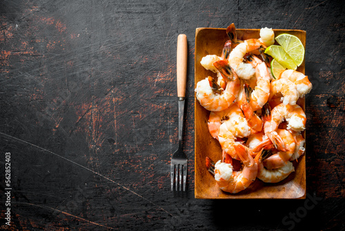 Fragrant shrimps on a wooden plate with a fork.