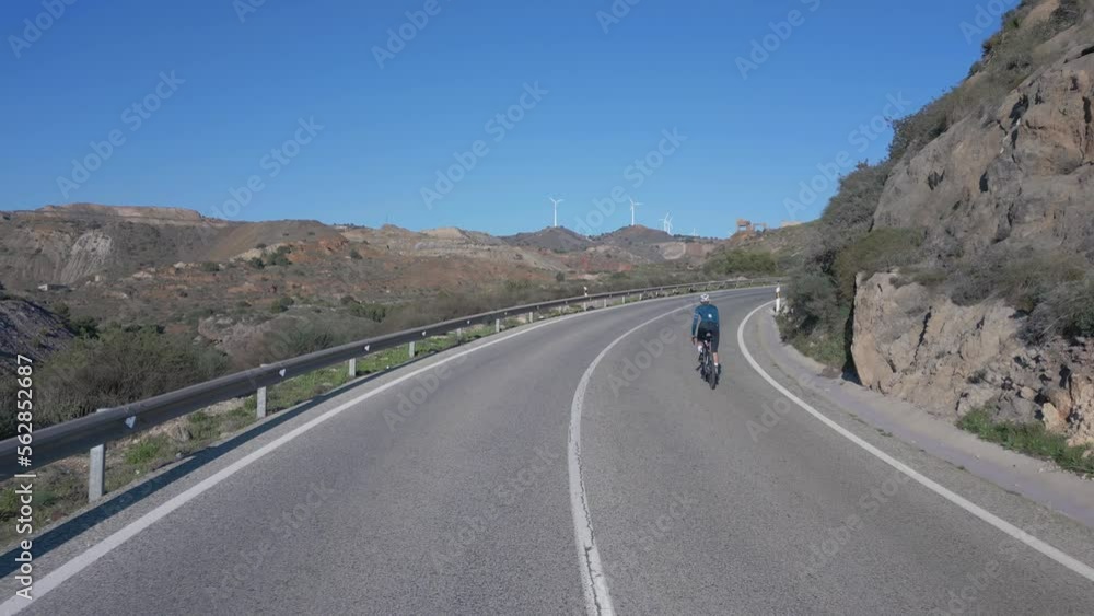 Camera follows female riding road bicycle while she trains in the mountains. Endurance training pushing pedals hard on uphill. Building strength and endurance. Cycling camp in Spain. Cartagena, Spain Camera follows female riding road bicycle while she trains in the mountains. Endurance training pushing pedals hard on uphill. Building strength and endurance. Cycling camp in Spain. Cartagena, Spain
