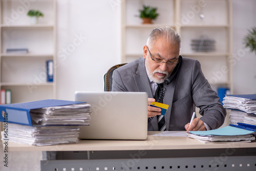 Old male employee holding credit card in the office