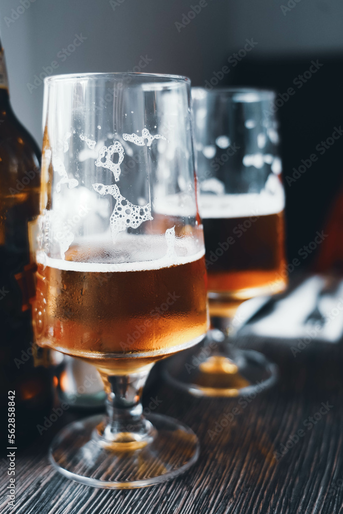 Two large glasses of cold beer. Goblets half full of amber beer with foam. Beer break in a bar with friends. Comfort, alcohol and a passion for good beer. Two large glasses of cold beer. Goblets half full of amber beer with foam. Beer break in a bar with friends. Comfort, alcohol and a passion for good beer.