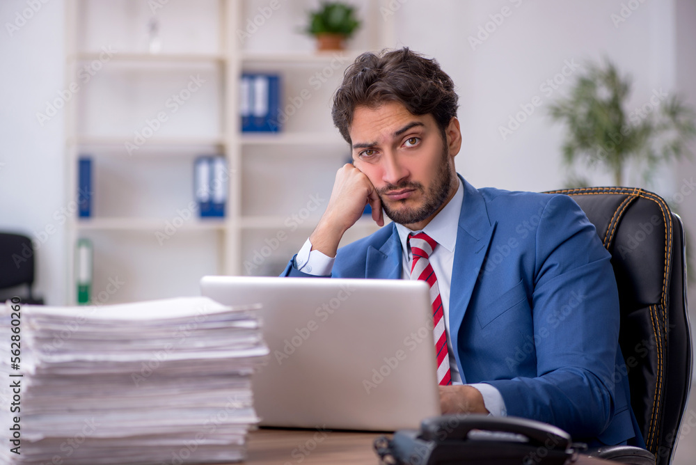 Young male employee and too much work in the office Young male employee and too much work in the office