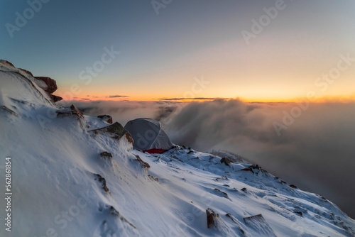 High Altitude Haven: Camping Above the Clouds on Snow-Covered Mountain Peak