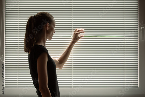 Photography woman looking peaking through bedroom office window blinds