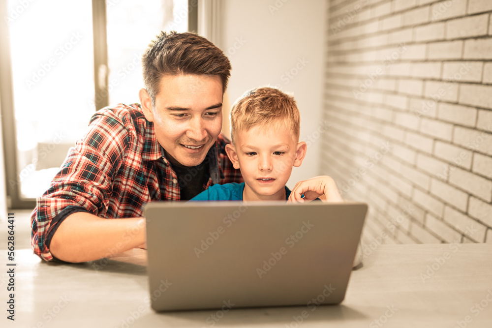 Father helping his son child do homework learning on computer 