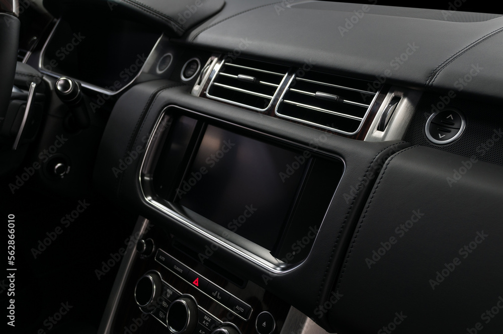 Car interior detail. Panel with multimedia screen, control buttons and air conditioner holes.